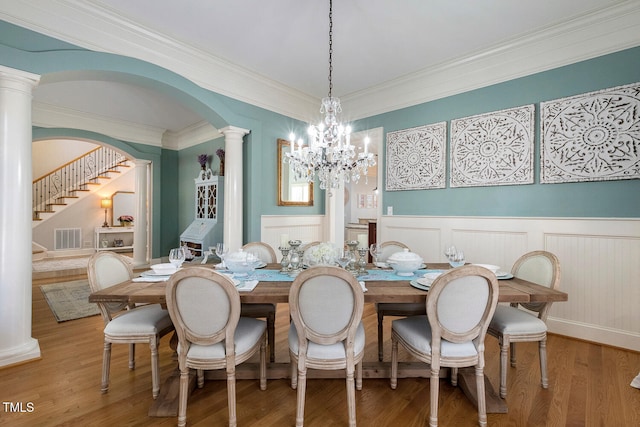 dining area featuring an inviting chandelier, crown molding, wood-type flooring, and decorative columns