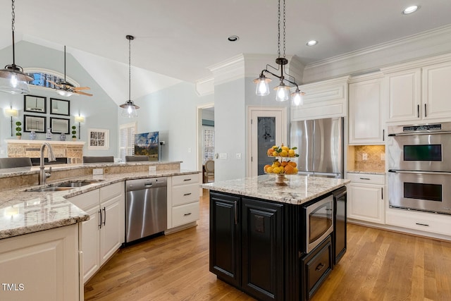 kitchen with a kitchen island, sink, hanging light fixtures, light stone counters, and stainless steel appliances