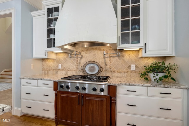 kitchen with premium range hood, white cabinetry, wood-type flooring, decorative backsplash, and stainless steel gas stovetop