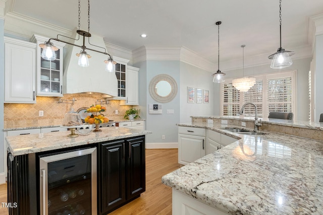 kitchen featuring sink, white cabinets, beverage cooler, hanging light fixtures, and a center island