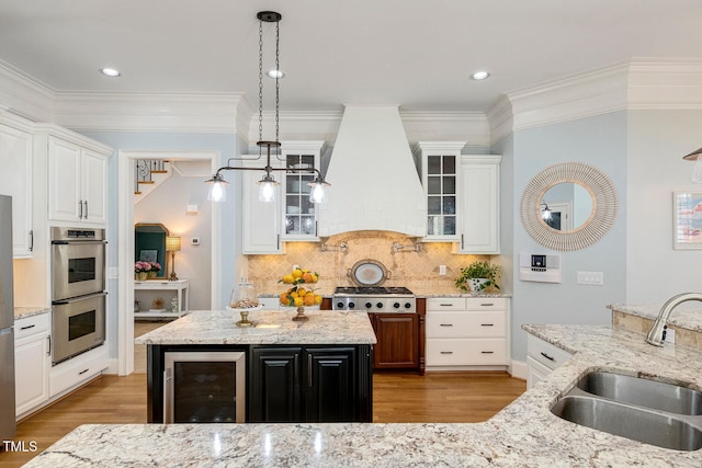 kitchen with sink, premium range hood, a center island, white cabinets, and beverage cooler