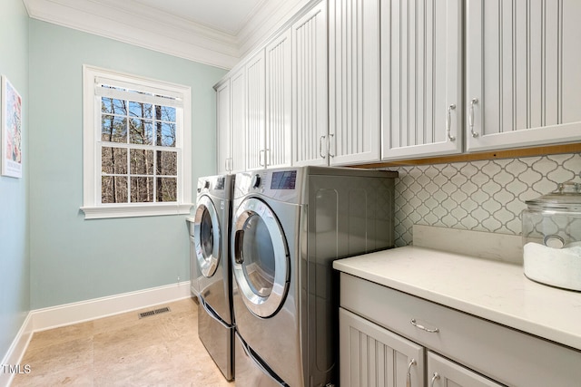 washroom featuring light tile patterned flooring, cabinets, ornamental molding, and washer and clothes dryer