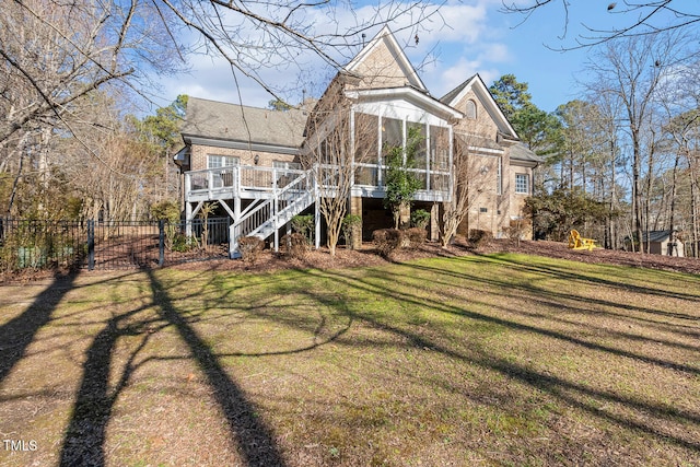 back of property featuring a sunroom, a deck, and a lawn