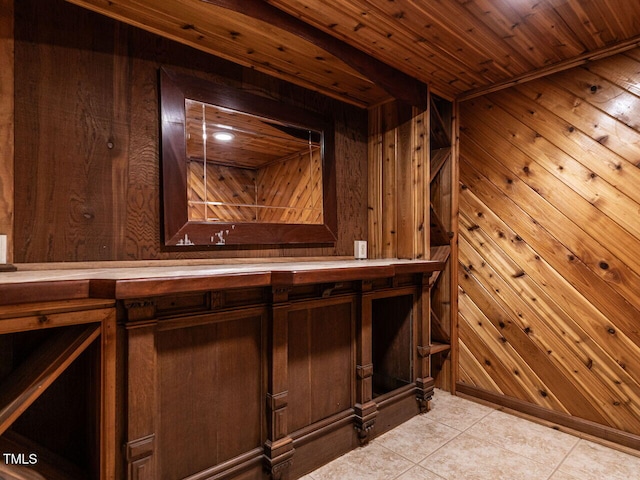 bar with light tile patterned floors, wooden walls, and wooden ceiling