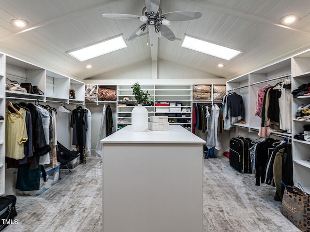 spacious closet featuring ceiling fan, lofted ceiling with skylight, and light wood-type flooring