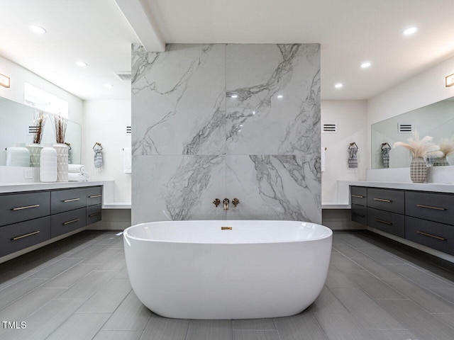 bathroom with vanity, a bathing tub, and tile walls