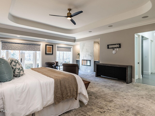 carpeted bedroom with crown molding, ceiling fan, a high end fireplace, and a tray ceiling