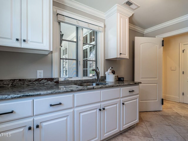 kitchen with white cabinetry, sink, crown molding, and dark stone counters