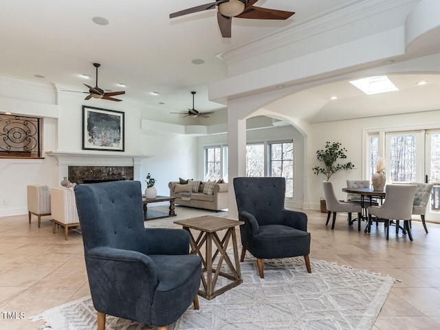 tiled living room with a premium fireplace, plenty of natural light, ceiling fan, and crown molding