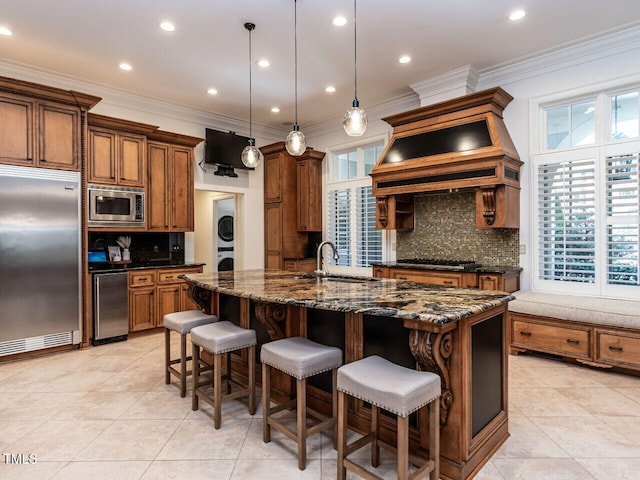 kitchen featuring built in appliances, stacked washer and dryer, a large island, and dark stone counters