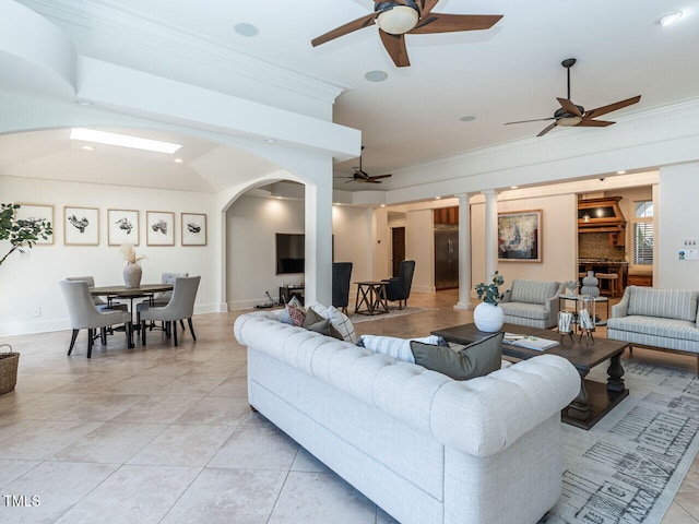 tiled living room with ornate columns, crown molding, and ceiling fan