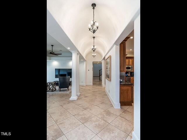 hallway with light tile patterned floors, a chandelier, and ornate columns