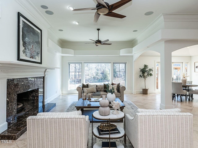 living room featuring a fireplace, ornamental molding, and ceiling fan