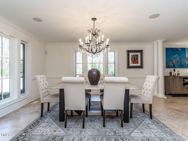 tiled dining space with an inviting chandelier, ornamental molding, and ornate columns