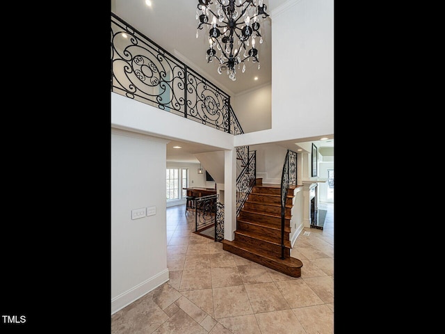 stairs with a towering ceiling, ornamental molding, tile patterned floors, and a notable chandelier