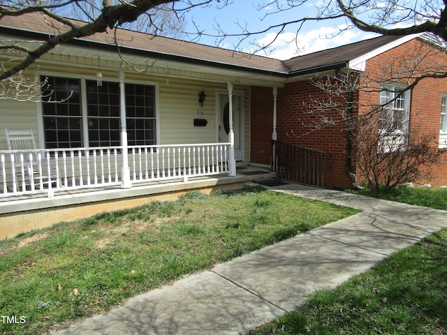 view of exterior entry with a porch and brick siding