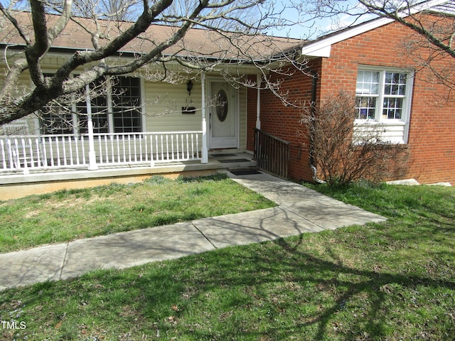 ranch-style house with brick siding, a porch, and a front yard