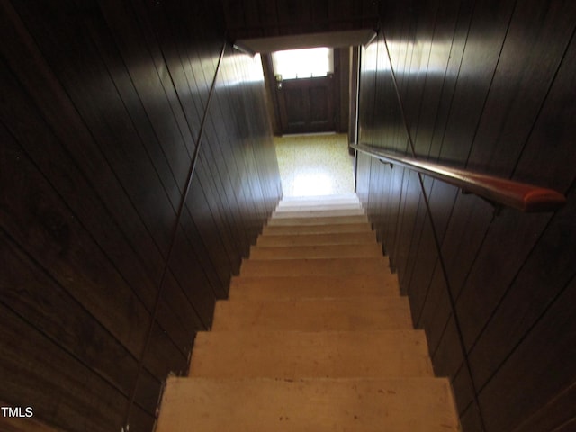 stairway featuring wood walls