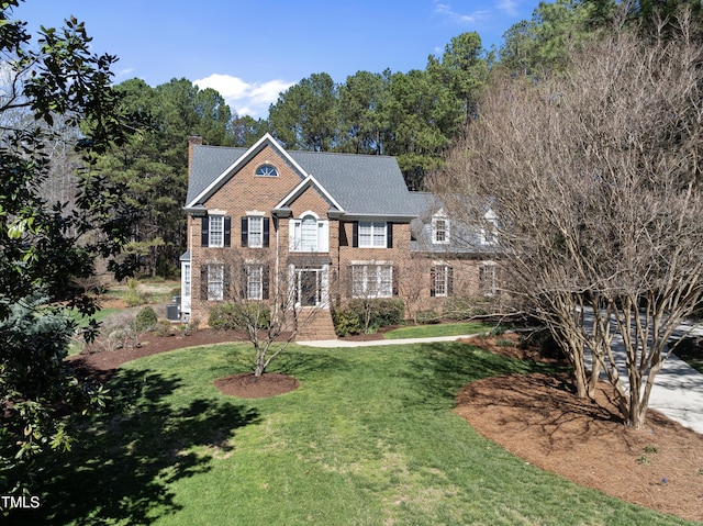 view of front of property featuring a front lawn, brick siding, and a chimney