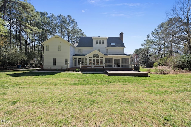 rear view of property with a lawn, a sunroom, and a chimney