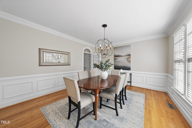 dining area with visible vents, a chandelier, ornamental molding, and light wood finished floors