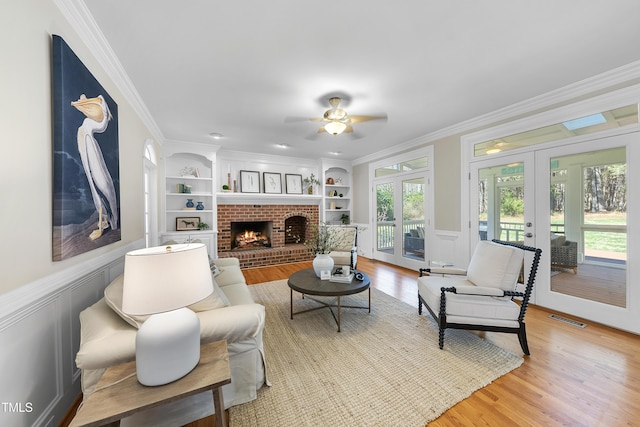 living area featuring crown molding, built in shelves, french doors, and visible vents