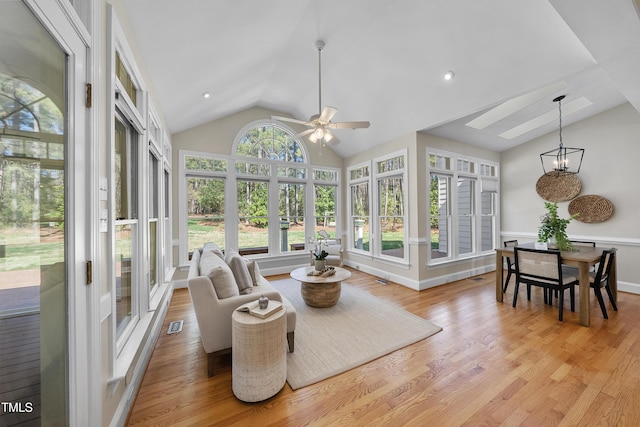 sunroom / solarium with visible vents, vaulted ceiling with skylight, and ceiling fan with notable chandelier