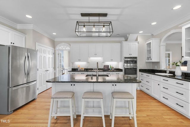 kitchen with white cabinets, appliances with stainless steel finishes, a kitchen breakfast bar, and a sink