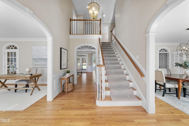 entryway with arched walkways, a notable chandelier, and ornamental molding