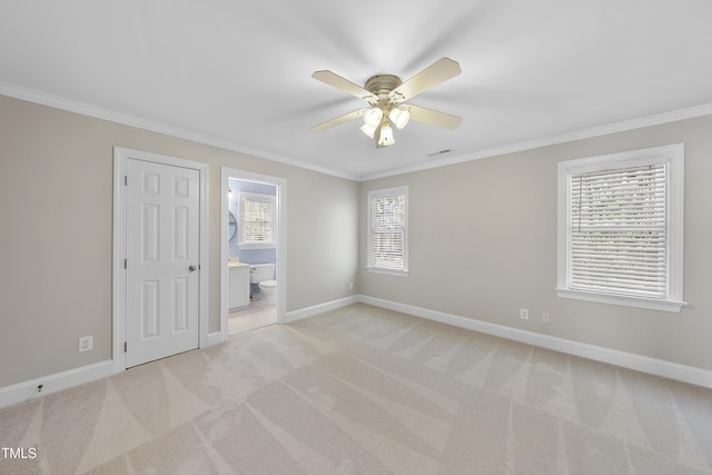 unfurnished bedroom featuring light carpet, multiple windows, baseboards, and ornamental molding