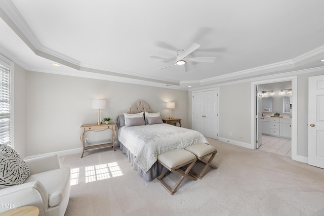 bedroom featuring connected bathroom, baseboards, a tray ceiling, ornamental molding, and light carpet