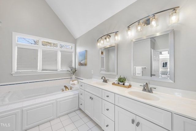 bathroom with a bath, vaulted ceiling, double vanity, and a sink