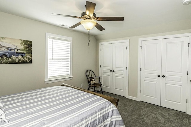 bedroom featuring multiple closets, ceiling fan, and dark colored carpet