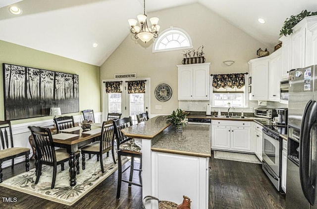 kitchen featuring a kitchen bar, sink, white cabinetry, a kitchen island, and stainless steel appliances