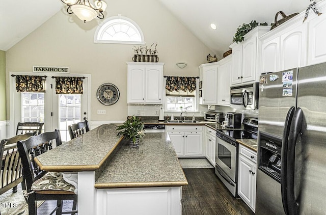 kitchen with sink, white cabinets, a kitchen bar, stainless steel appliances, and a healthy amount of sunlight