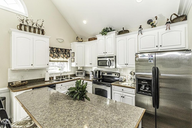 kitchen with sink, appliances with stainless steel finishes, backsplash, white cabinets, and vaulted ceiling