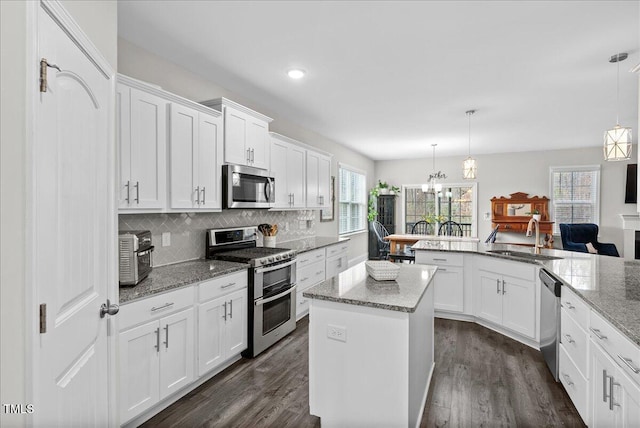 kitchen featuring stainless steel appliances, kitchen peninsula, sink, and hanging light fixtures