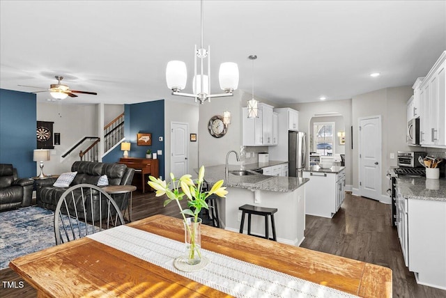 dining space with ceiling fan with notable chandelier, dark hardwood / wood-style flooring, and sink