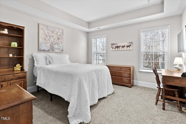 carpeted bedroom featuring a tray ceiling and multiple windows