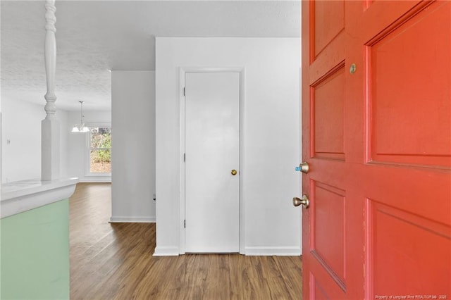 hall with hardwood / wood-style flooring, an inviting chandelier, and a textured ceiling