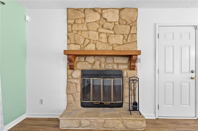 room details featuring wood-type flooring, heating unit, a textured ceiling, and a fireplace