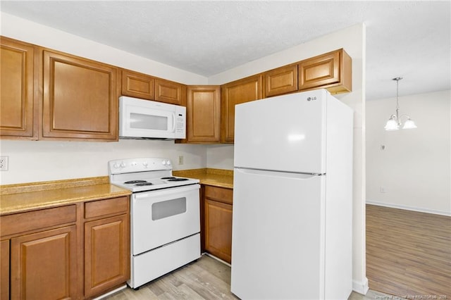 kitchen with light wood-type flooring, a chandelier, white appliances, and decorative light fixtures