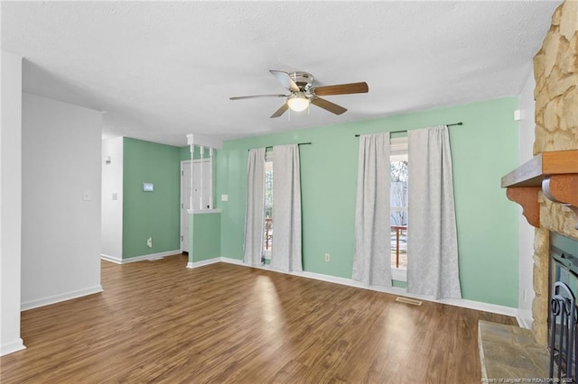 unfurnished living room with hardwood / wood-style flooring, a fireplace, a textured ceiling, and ceiling fan