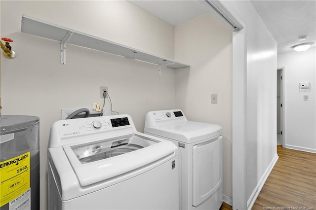 clothes washing area featuring hardwood / wood-style floors, washer and clothes dryer, and electric water heater