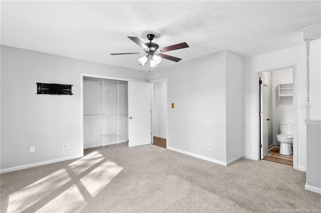 unfurnished bedroom featuring ceiling fan, carpet flooring, ensuite bath, and a closet