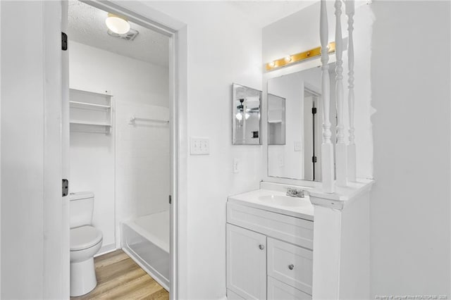 full bathroom featuring toilet, tiled shower / bath, a textured ceiling, vanity, and hardwood / wood-style floors