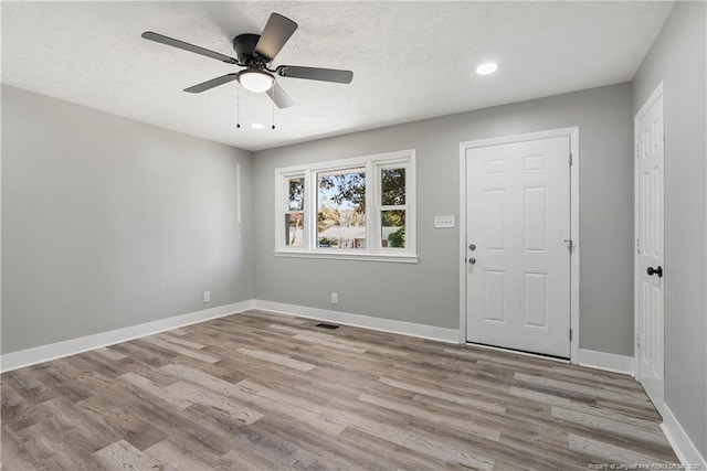 entrance foyer with ceiling fan, a textured ceiling, and light wood-type flooring