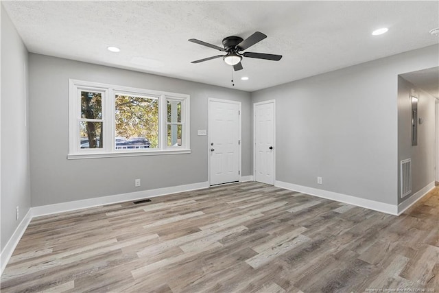 unfurnished room with ceiling fan, light hardwood / wood-style flooring, and a textured ceiling