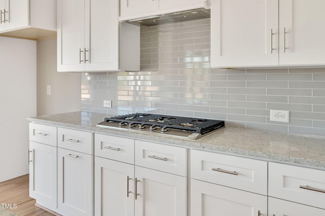 kitchen featuring light stone countertops, stainless steel gas cooktop, exhaust hood, and white cabinets