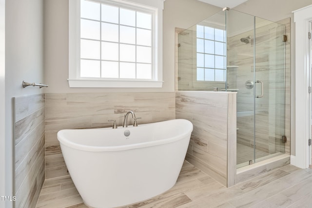 bathroom featuring tile walls, independent shower and bath, and a healthy amount of sunlight